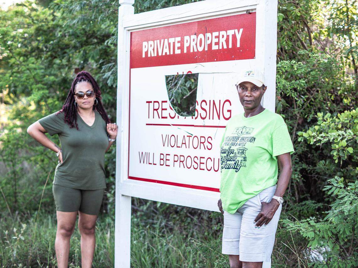 Krystal Adderley, left, a Miami resident and daughter of David Adderley, stands next to a “No Trespassing” sign erected by 3ABN in Long Island, Bahamas, with her cousin Norma Fernander, who lives in Nassau. The family, which owned the property for four generations, alleges that 3ABN misled David Adderley into signing away 400 acres.