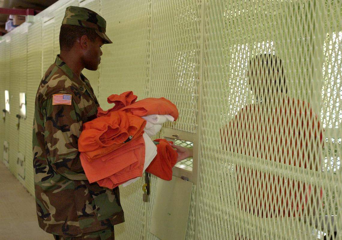 In this photo reviewed by the US military, a guard gives clean clothes and linen to a detainee before prayer in Camp Delta on June 30, 2004.