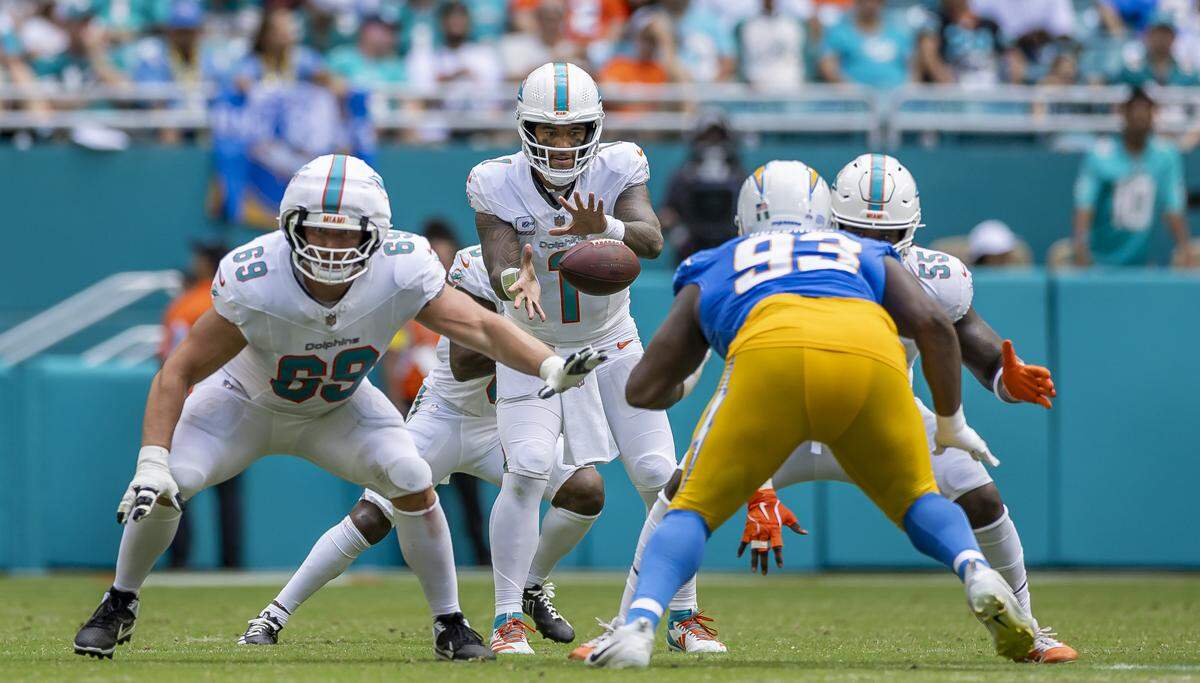 Miami Dolphins quarterback Tua Tagovailoa (1) receives the ball as Los Angeles Chargers defensive tackle Otito Ogbonnia (93) tries to tackle him in the second half of their NFL game at Hard Rock Stadium on Sunday, Oct. 12, 2025, in Miami Gardens, Fla.