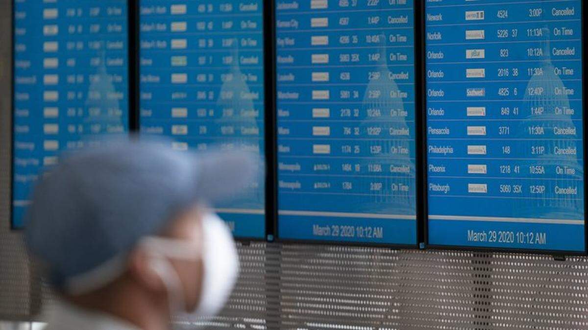 Traveler wearing a face mask examines the flight board at Reagan National Airport in Washington, D.C.