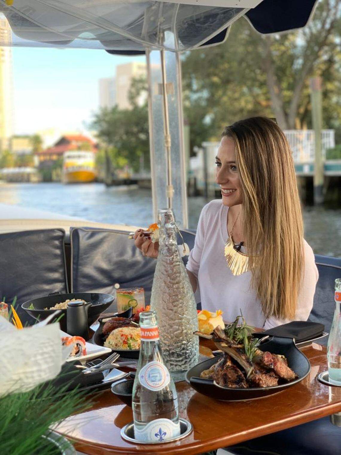 A woman is surrounded by food and drink aboard a gondola on the water in Fort Lauderdale.