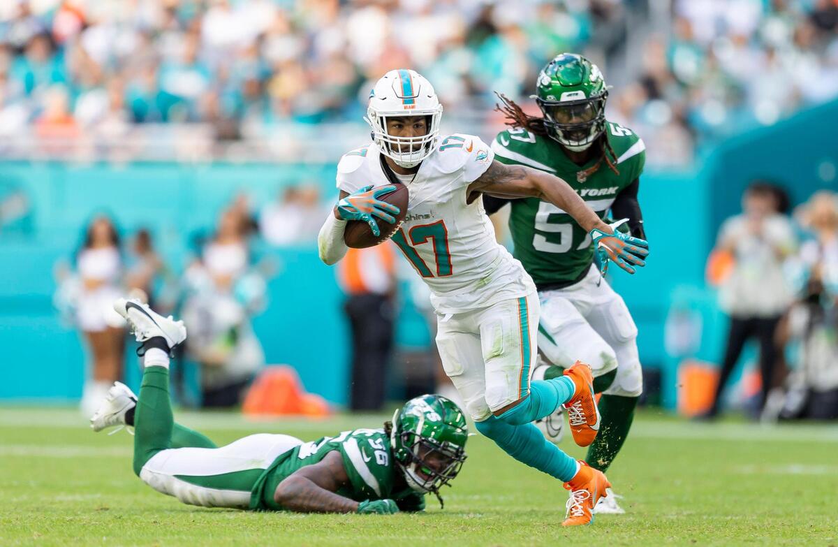 Miami Dolphins wide receiver Jaylen Waddle (17) runs with the ball as New York Jets linebackers C.J. Mosley (57) and Quincy Williams (56) try to stop him in the third quarter at Hard Rock Stadium on Sunday, Dec. 17, 2023, in Miami Gardens, Fla.