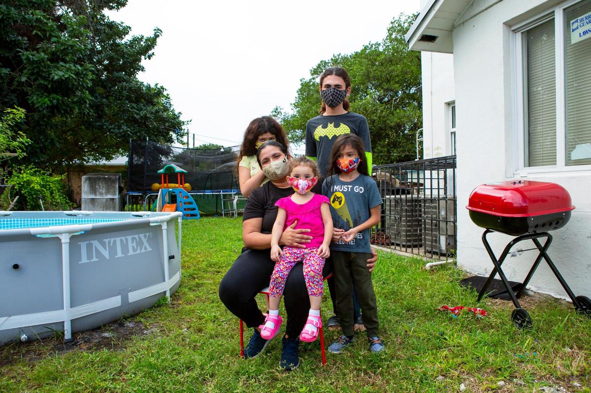 Single mother Kandy Gomez, 39, sits with her kids Christian Arias, 13, Jeslin Arias, 10, Gabriel Gomez, 7, and Brianna Alvarado, 2, outside their house in Liberty City on Saturday, Nov. 21, 2020.