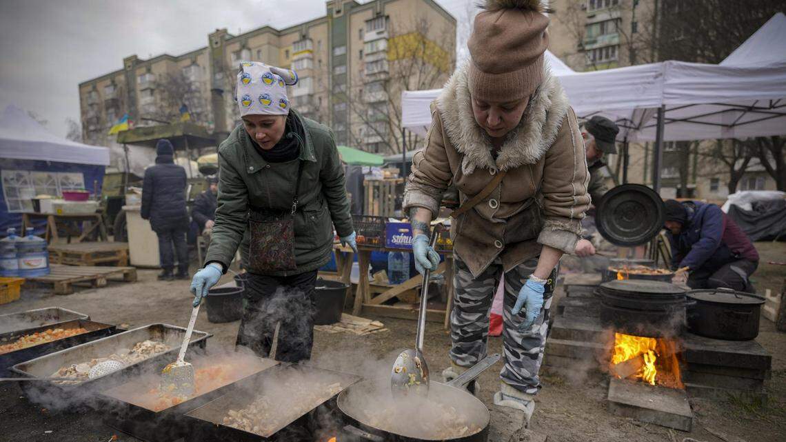 People cook outdoors for Ukrainian servicemen and civil defense members serving in Kyiv.