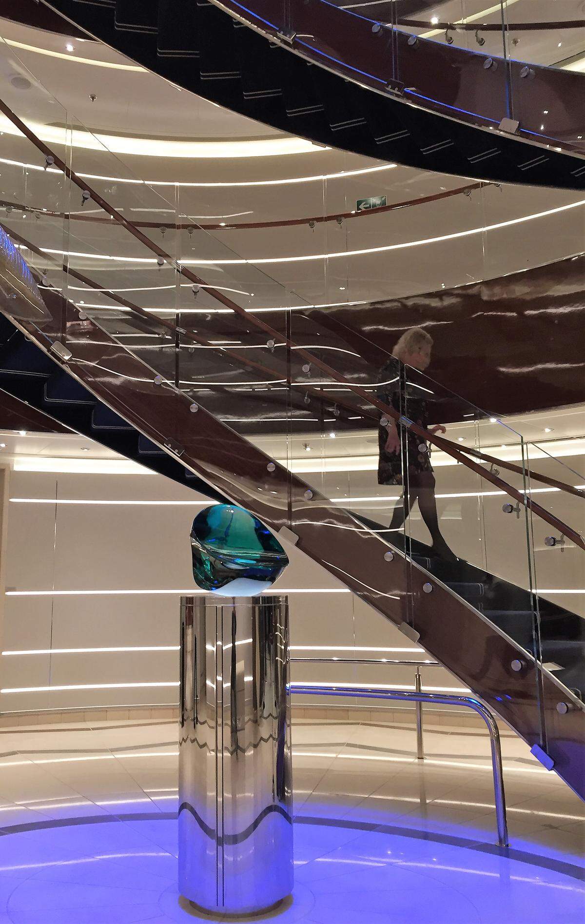 Atrium stairway on Seabourn Ovation, designed by Adam Tihany: “No matter what you wear when you walk down the stairway, you straighten up, make your grand entrance, because you look and feel great.” The art at the base is "Warrior The Second," created by Luciano Vistosi from polished and hammered lagoon green crystal.