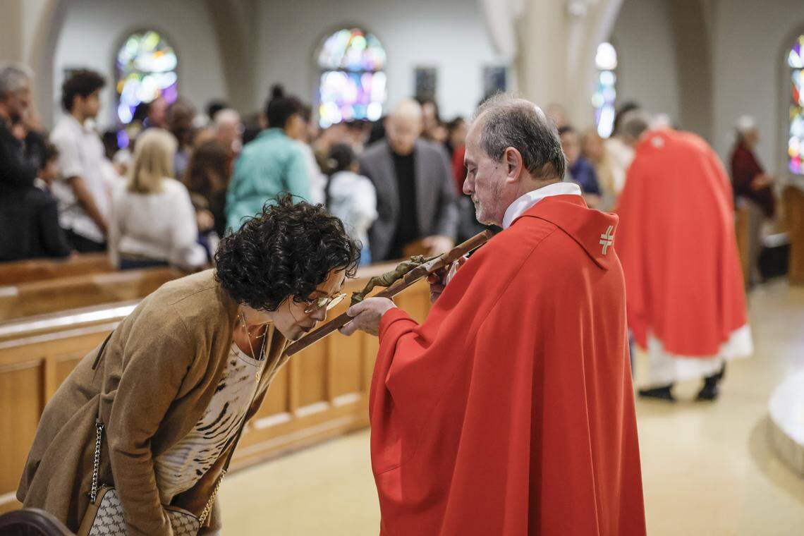 A parishioner kisses the crucifix held by the Rev. Oswaldo Agudelo as Archbishop Thomas Wenski presides over Good Friday of the Lord’s Passion at St. Mary Cathedral. The service was followed by the Stations of the Cross procession on Friday, April 3, 2026, in Miami.