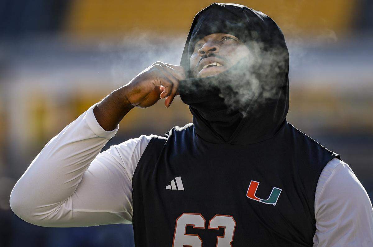 A mist of cold air is seen as Miami Hurricanes offensive lineman Samson Okunlola (63) exhales during pregame warm-ups before the NCAA football game against the Pittsburgh Panthers at Acrisure Stadium in Pittsburgh, PA, on Saturday, November 29, 2025.