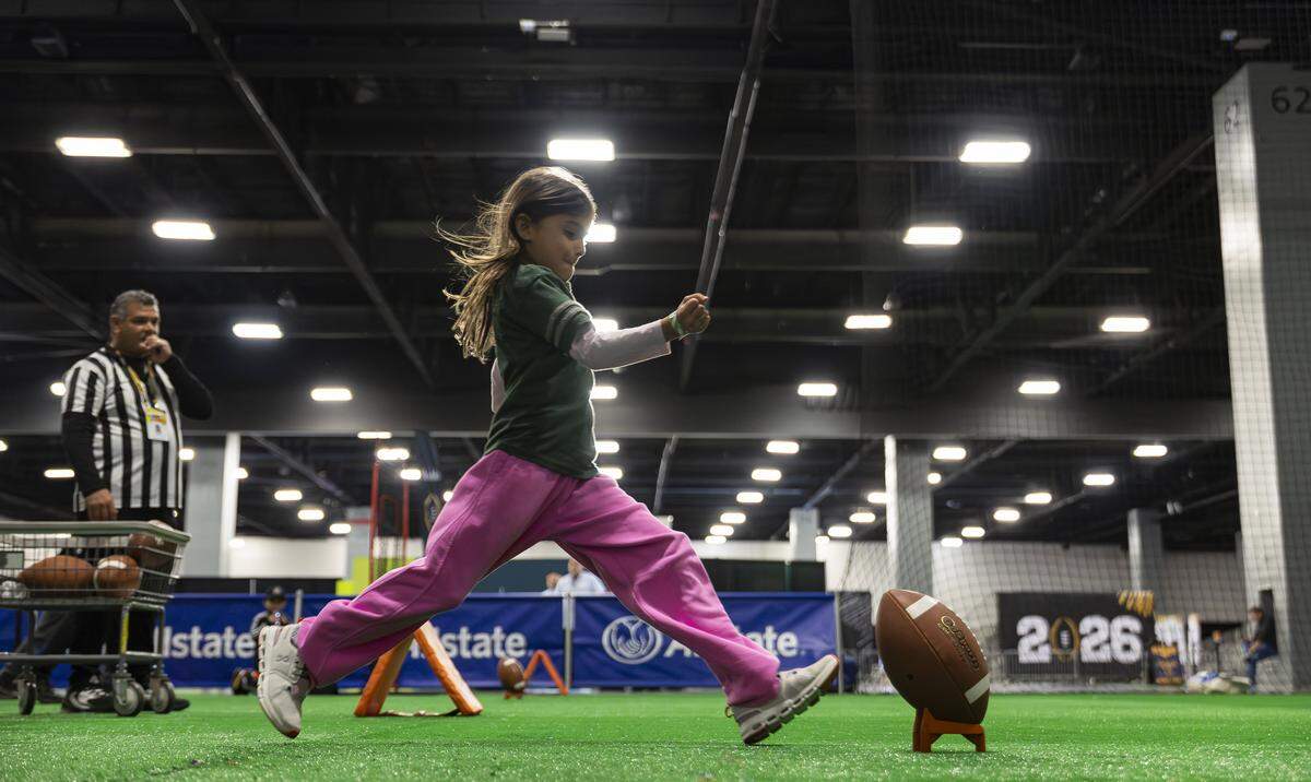 Isabella McCarthy, 9, kicks a football while visiting the Playoff Fan Central at the Miami Beach Convention Center on Friday, Jan. 16, 2025, in Miami Beach, Fla. Fans can visit the event ahead of the College Football Playoff National Championship Game between the Miami Hurricanes and the Indiana Hoosiers and enjoy a variety of family-friendly interactive experiences.