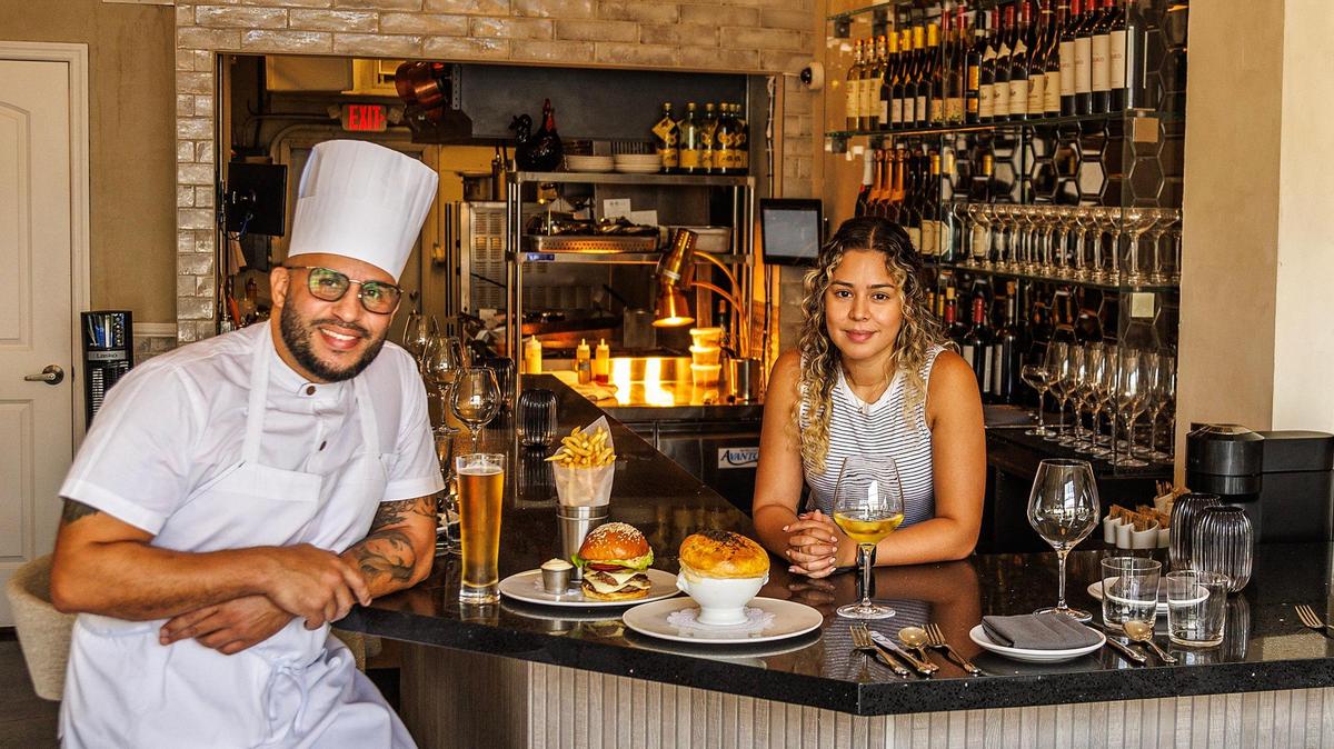 Chef/owner Nuno Grullon and his wife and co-owner Crystal Paez display a Grand Central burger with Fries and truffle chicken pot pie at the bar of their new restaurant Grand Central.