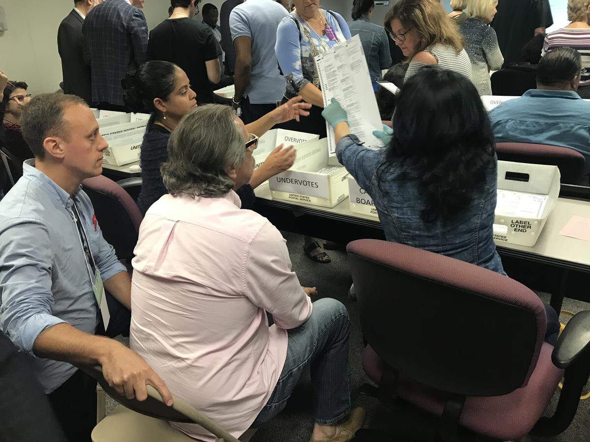 Shortly after 9 p.m., Miami-Dade began hand recounting more than 10,000 ballots cast in the U.S. Senate race. The ballots were only those where a scanning machine determined no vote had been cast in the senate contest, or the voter had voted for more than one candidate. In this photo, one of 20 vote-screening teams, surrounded by partisan observers, begin sorting the ballots for the county’s three-member canvassing board.
