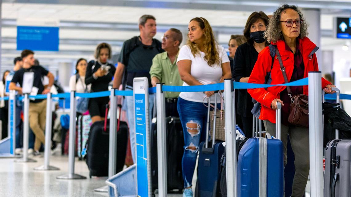 Los viajeros esperan en filas en el nivel de salidas dentro del Aeropuerto Internacional de Miami en Miami, Florida, el miércoles 23 de noviembre de 2022.