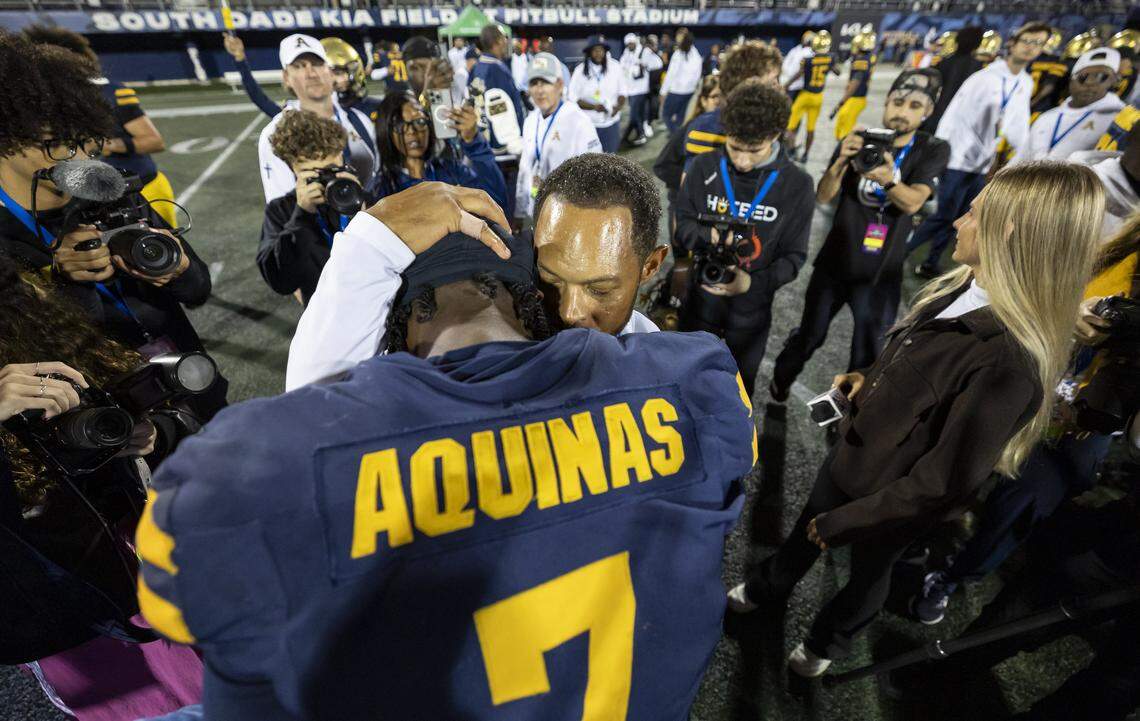 St. Thomas Aquinas Raiders head coach Roger Harriott celebrates with quarterback Mason Mallory (7) after they defeated the Lakeland Dreadnaughts in their Class 5A state championship football game at Pitbull Stadium on Thursday, Dec. 11, 2025, in Miami, Fla.