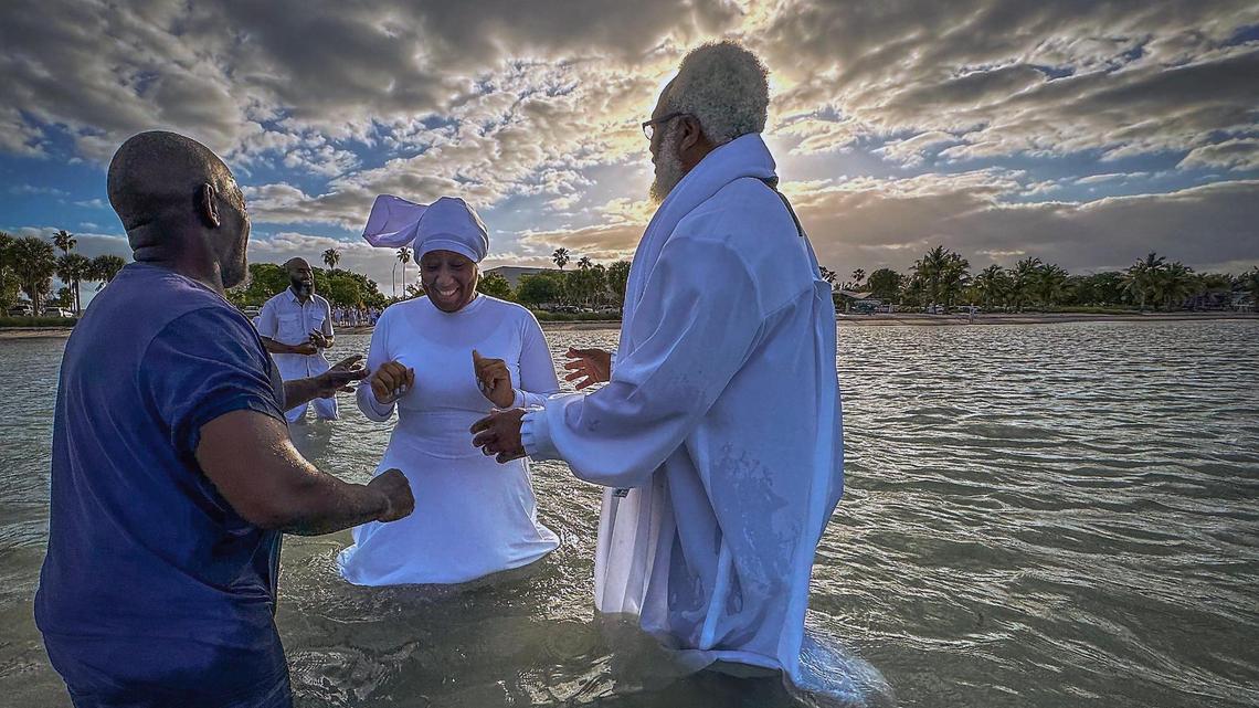Victoria Everett, center, member of the Jesus Christ True Church walks towards Apostle Leon Everett, left, and Minister Allen Mushgrove during baptism on Hobie Beach. Jesus Christ True Church baptized nearly 40 individuals on Easter Sunday.