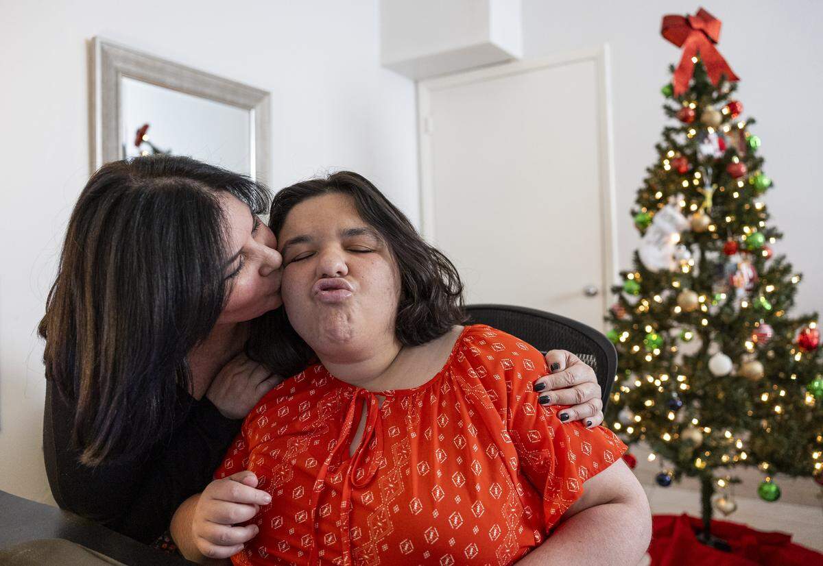 Bessie Oropesa gives her daughter, Amanda, 30, a kiss on the cheek at their home on Friday, Dec. 5, 2025, in Miami, Fla. Amanda, who is a person with autism and a Wish Book participant, is in need of new clothes and any help with groceries.