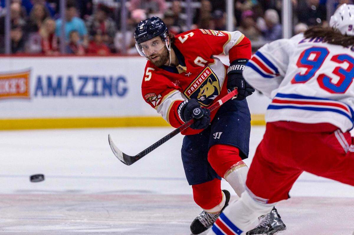 Florida Panthers defenseman Aaron Ekblad (5) passes the puck past New York Rangers center Mika Zibanejad (93) during the first period of an NHL game at Amerant Bank Arena on Monday, Dec. 30, 2024, in Sunrise, Fla.