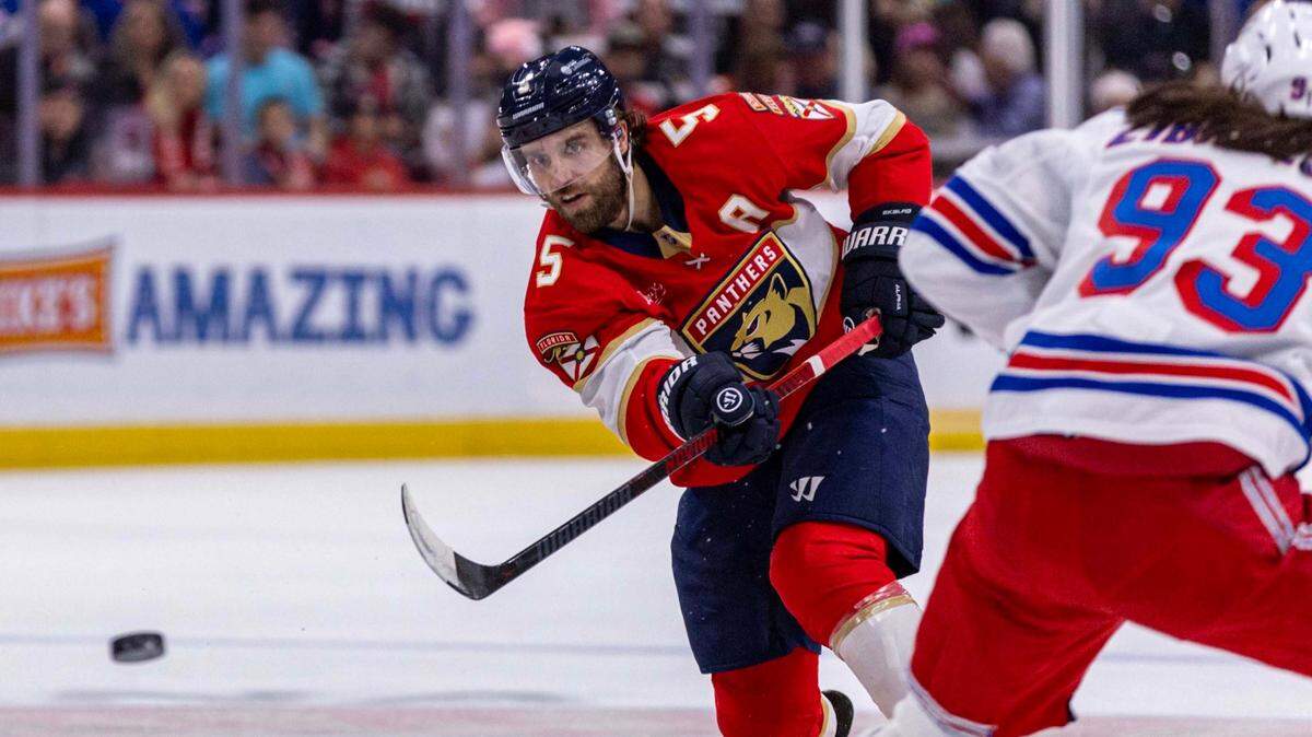 Florida Panthers defenseman Aaron Ekblad (5) passes the puck past New York Rangers center Mika Zibanejad (93) during the first period of an NHL game at Amerant Bank Arena on Monday, Dec. 30, 2024, in Sunrise, Fla.