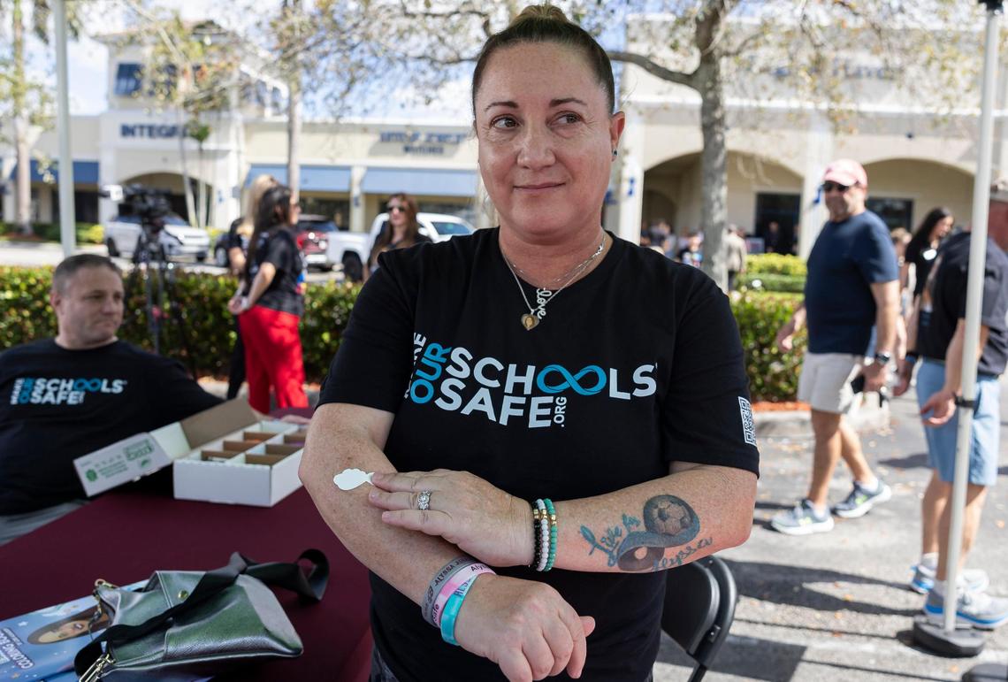 Lori Alhadeff, the mother of Alyssa Alhadeff and a Broward County School Board member, applies a temporary tattoo inspired by her daughter during the ‘Forever in Our Hearts’ commemoration event outside of the Eagles’ Haven Wellness Center on Friday, Feb. 14, 2025, in Coral Springs, Fla. The event aims to honor the 17 lives lost during the Marjory Stoneman Douglas High School shooting in 2018 and their families.