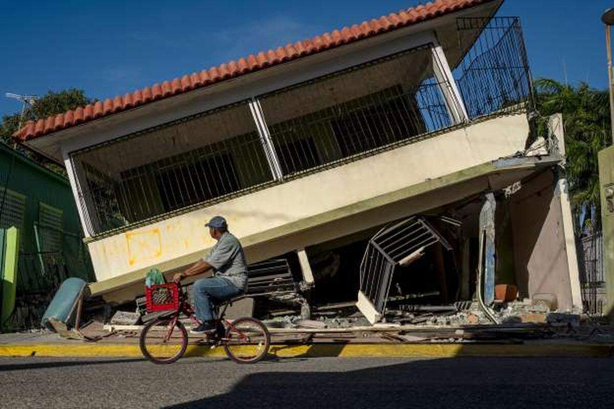 Un hombre pasa en su bicicleta frente a una casa colapsada en Guánica, Puerto Rico, el 15 de enero de tras un poderoso terremoto que golpeó la isla.