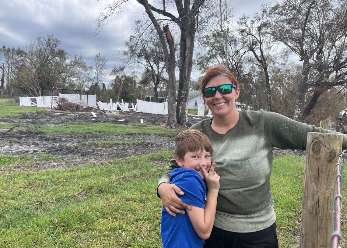 Chelsea Green and her son can smile despite what is behind her, damage to her Desoto County property, inflicted by Hurricane Ian.