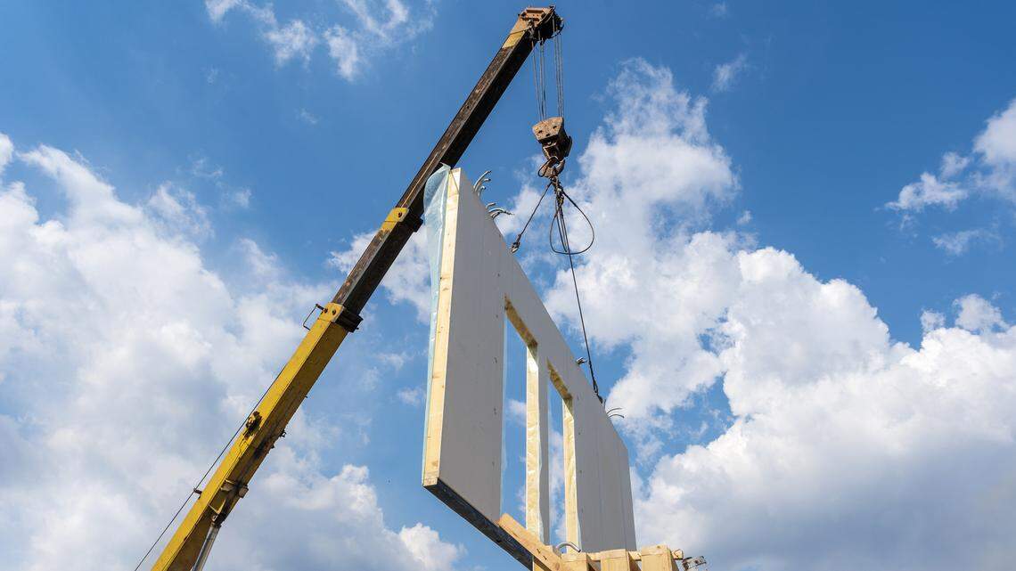 Process of crane construction of new and modern modular house from composite sip panels against background with beautiful blue sky