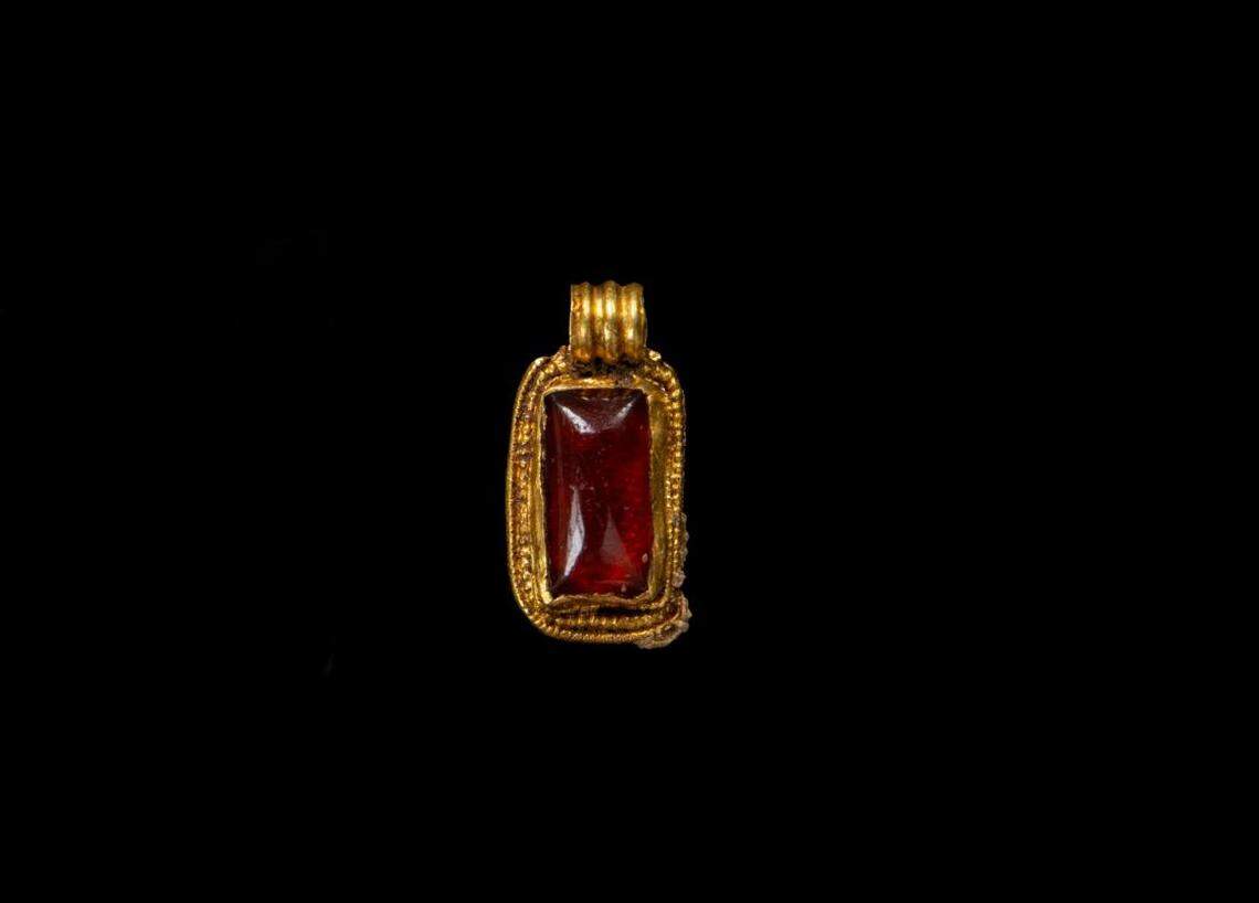 A gold pendant with a garnet at its center that was discovered in the grave.