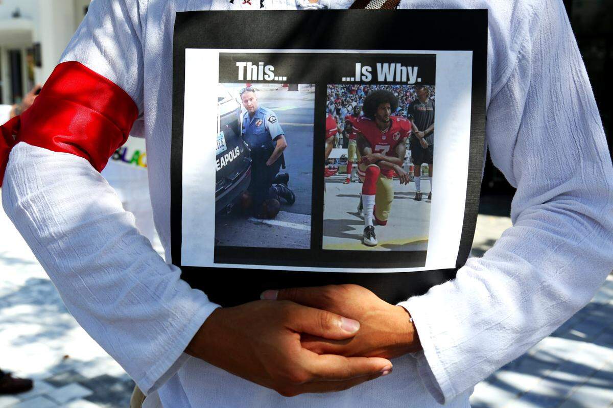 A protester holds a sign at the intersection of Coral Way and 42nd Avenue during a demonstration against police brutality in Coral Gables, Florida.