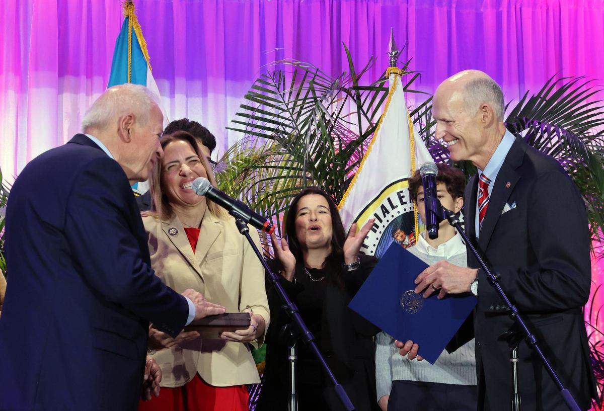 Property Appraiser Tomás Regalado removes his hand off a Bible held by his daughter, Miami-Dade Commissioner Raquel Regalado, center left, after taking the oath of affice administered by U.S. Sen. Rick Scott, right, on Jan. 13, 2025, during an installation ceremony for the supervisor of elections, tax collector and property appraiser at Milander Auditorium in Hialeah, Florida.