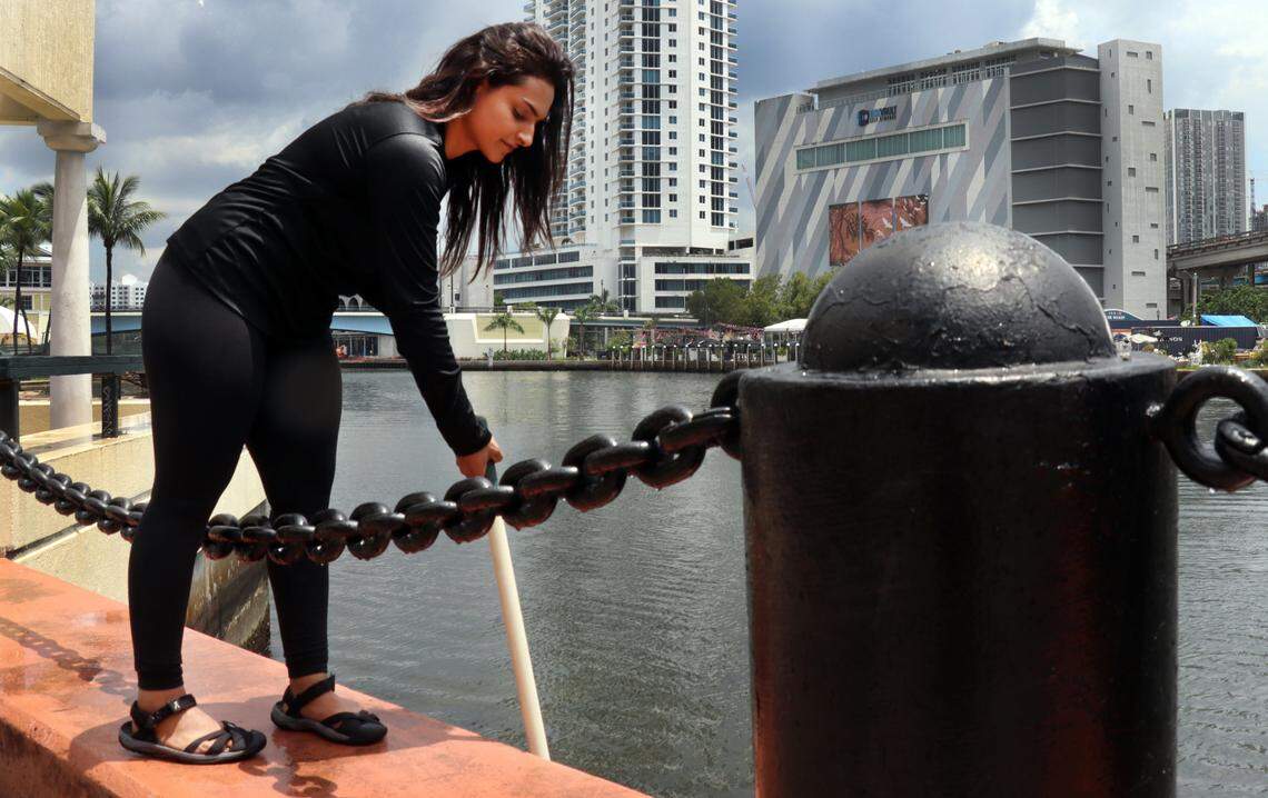 Aliza Karim, Miami Waterkeeper’s water quality research manager, dips a 100 milliliter bottle into the canal at Jose Marti Park Thursday, June 29, in Miami, Fla.