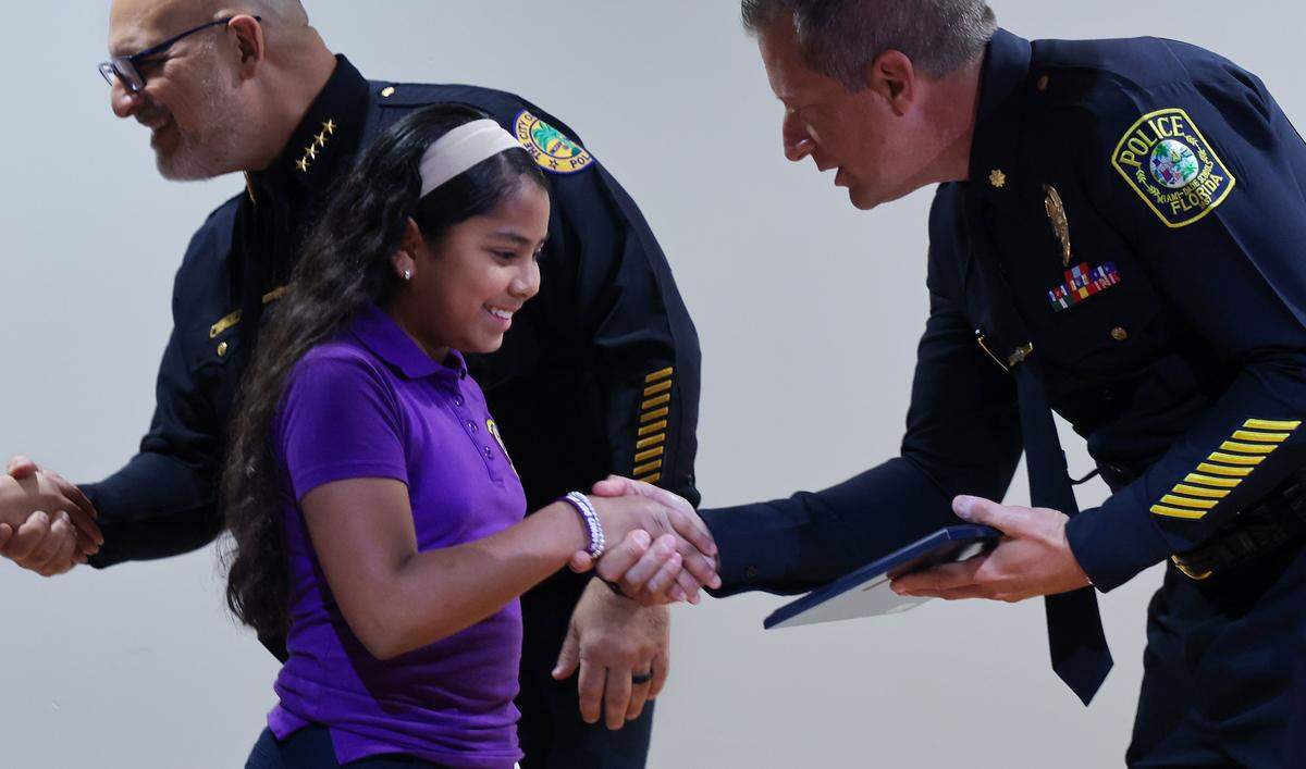 Meredith Ortiz, center, shakes the hands of law enforcement officers as she and family go on stage to receive her award. The Do The Right Thing Program and Miami Police honored nine outstanding students out of over 700 nominees for their courage, compassion, and leadership inside the auditorium of the Chief Clarence Dickson Police College on Wednesday, January 21, 2026, in Miami, Florida.