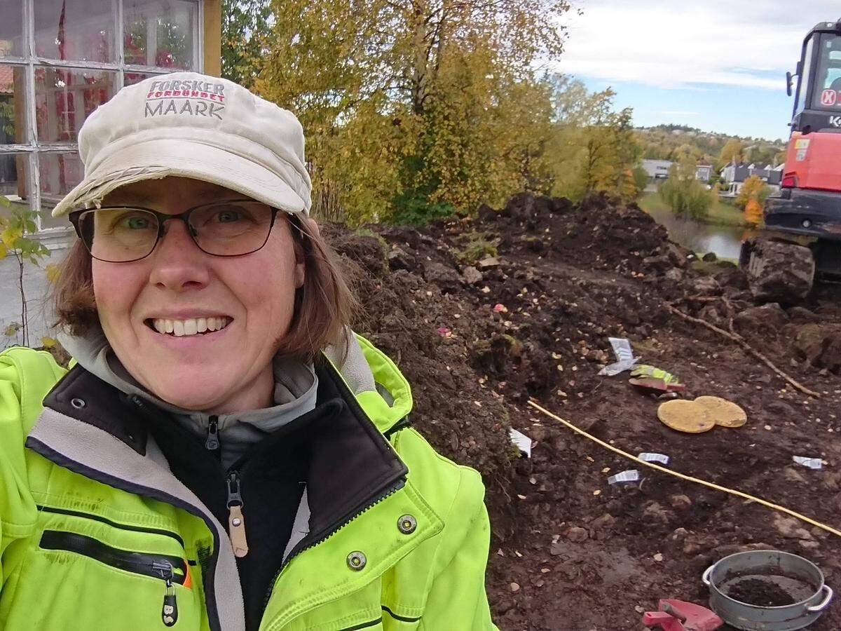 An archaeologist poses in front of the Viking grave.