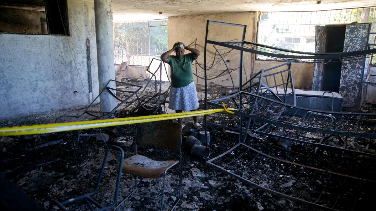 A staff worker of the Orphanage of the Church of Bible Understanding holds her head in disbelief amid the charred children’s home in Kenscoff, on the outskirts of Port-au-Prince, Haiti, Friday, Feb. 14, 2020. A fire swept through this orphanage run by a Pennsylvania-based nonprofit group, killing 15 children, according to healthcare workers.