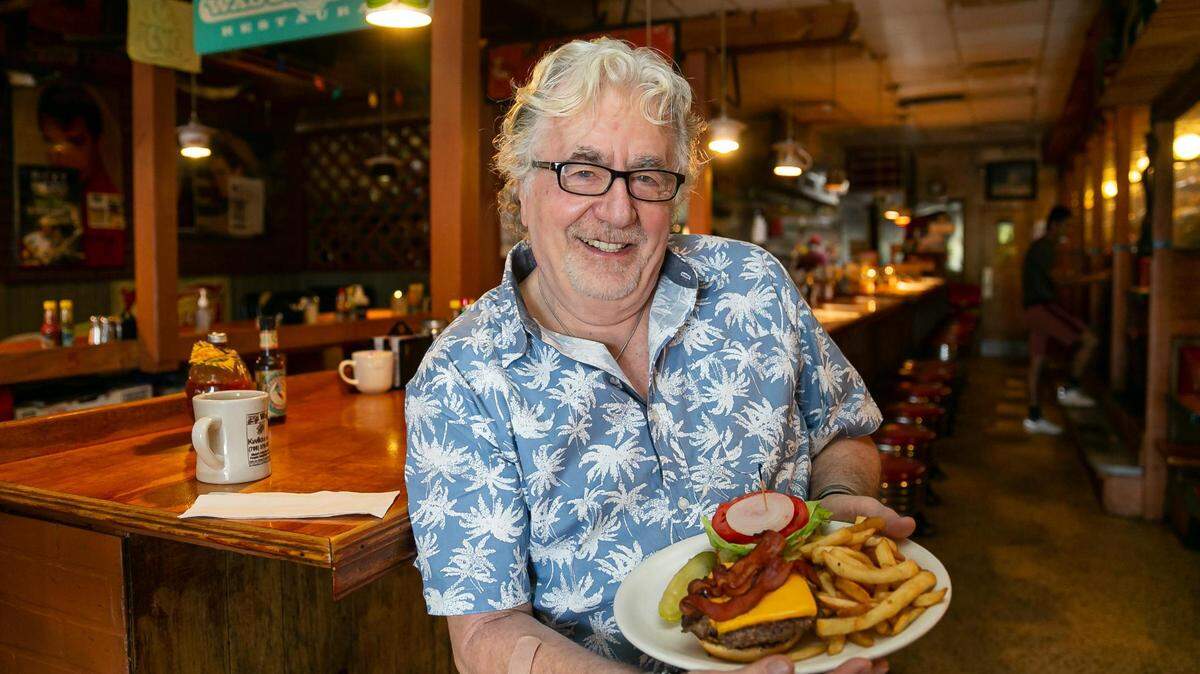 Walter 'Wally' Muench, propietario del restaurante Wagons West, enseña una hamburguesa con queso y tocino en su negocio, el viernes 1 de julio de 2022 en Pinecrest, Florida.