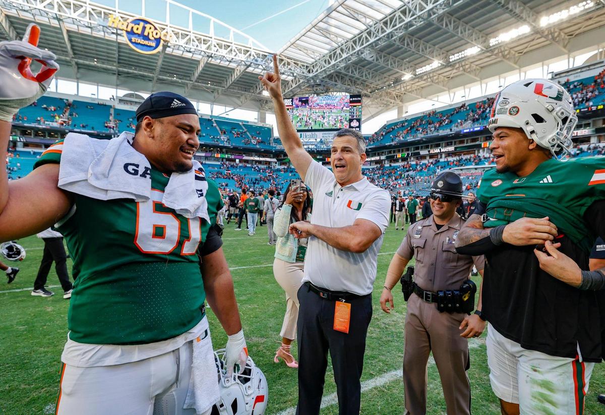 Miami Hurricanes head coach Mario Cristobal celebrates the win against the Wake Forest Demon Deacons with offensive lineman Francis Mauigoa (61) and tight end Elijah Arroyo (8) in the second half of their NCAA game in Miami Gardens, Florida, on Saturday, November 23, 2024.