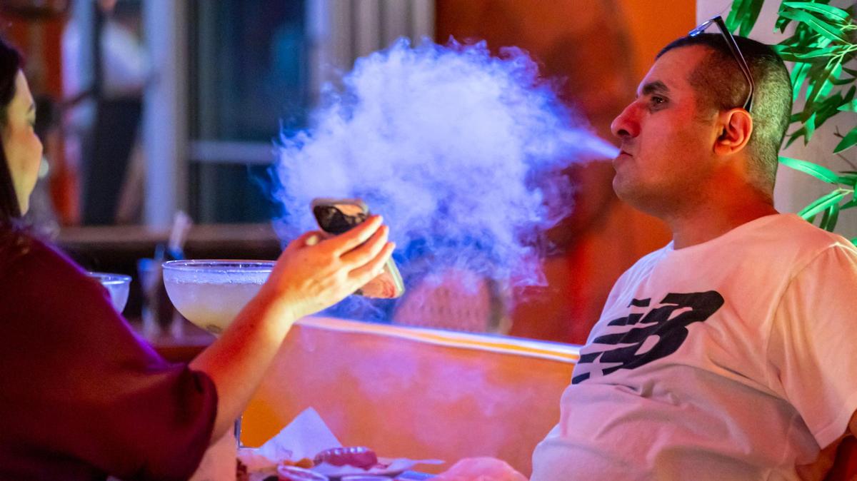 A man exhales hookah smoke at the outdoor patio of the Edison Hotel on Ocean Drive on Dec. 1.