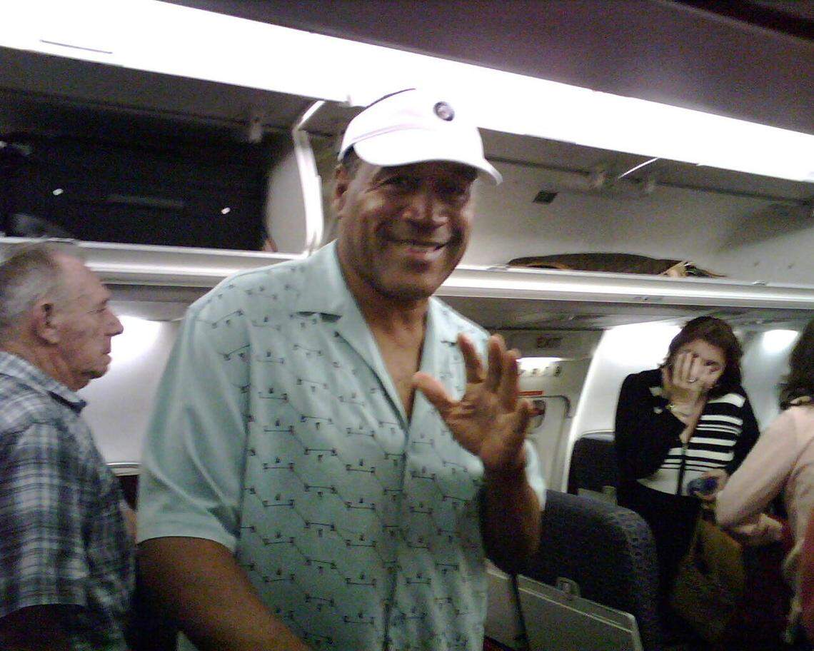 O.J. Simpson waves to the photographer, Miami Herald reporter Evan Benn. Both where on a plane flying from Las Vegas to Florida. Benn was covering O.J. Simpson’s preliminary hearing.