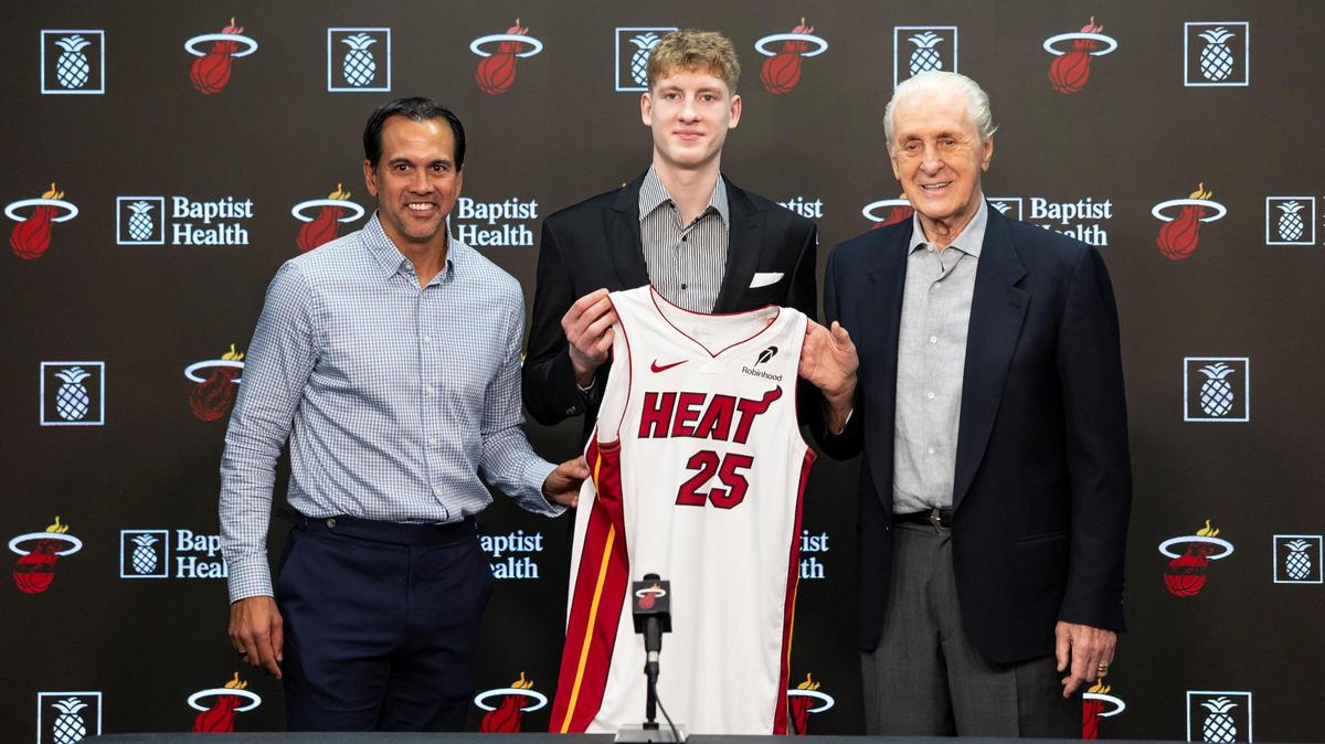 Kasparas Jakucionis, seleccionado en primera ronda del draft de Miami Heat, sostiene su camiseta junto al presidente del equipo, Pat Riley, y el entrenador en jefe Erik Spoelstra durante su conferencia de prensa presentativa en el Kaseya Center el 27 de junio de 2025, en Miami.