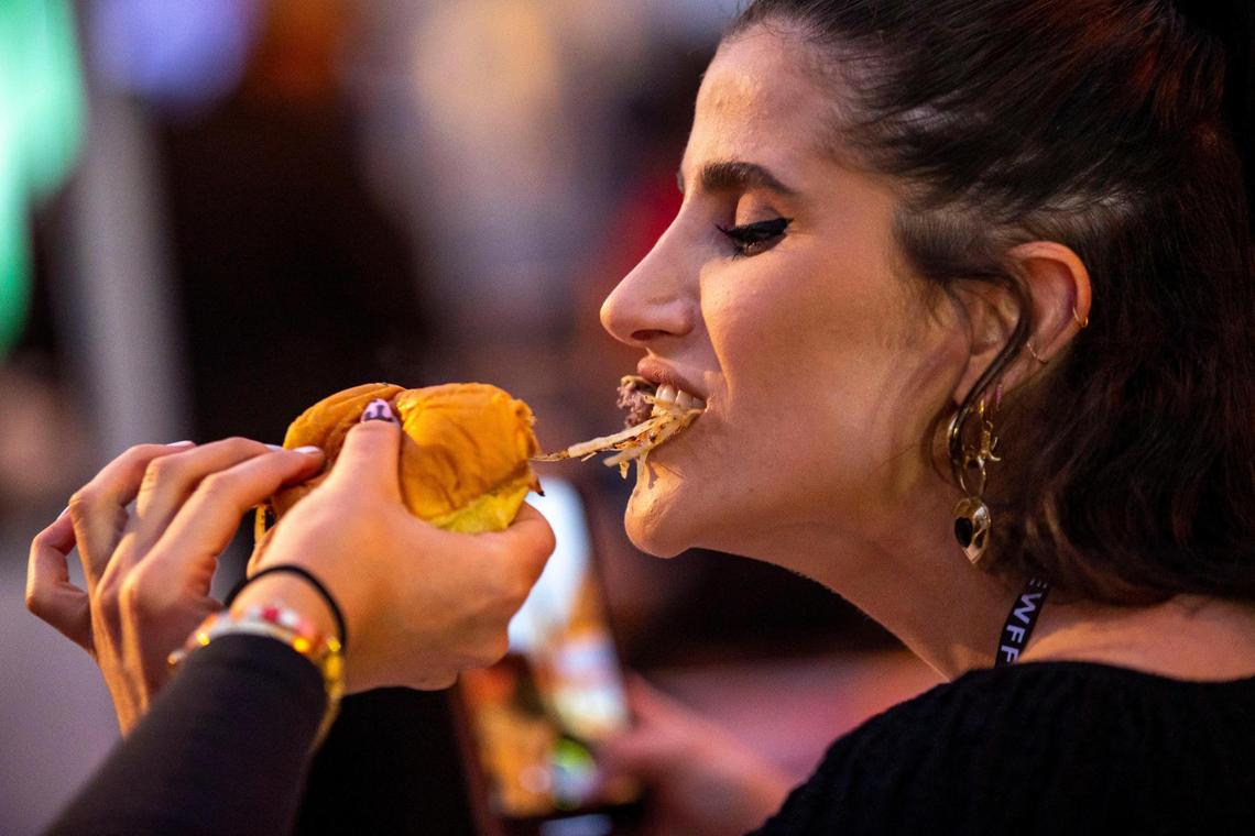 Emilie Sobel, de 29 años, le da un mordisco a la hamburguesa de su amigo durante el festival de comida South Beach Wine & Burger Bash.