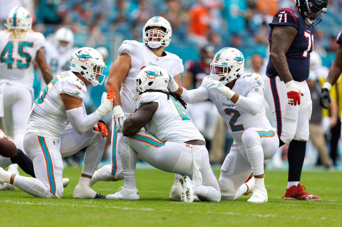 Miami Dolphins players Jaelan Phillips (15) Melvin Ingram (6) Bradley Chubb (2) and Zach Sieler (92) reacting after a defensive play during first quarter of an NFL football game against the Houston Texans at Hard Rock Stadium on Sunday, November 27, 2022 in Miami Gardens, Florida.