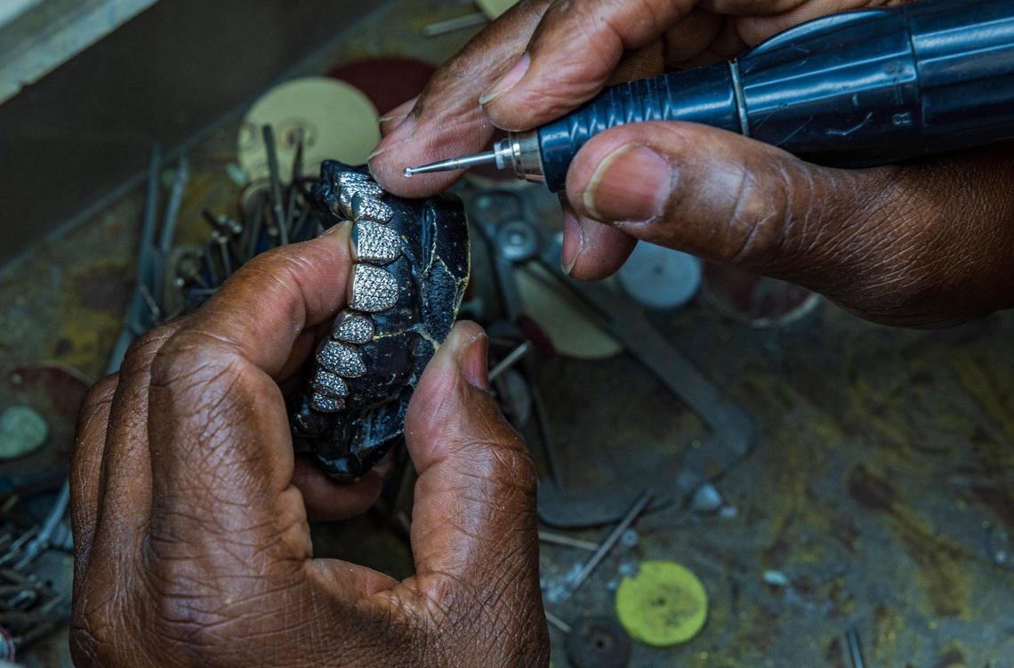 Orlando Plein works on a set of grillz using 18-karat white gold and diamonds in his shop at Lando Golds that specializes in making custom gold grillz.