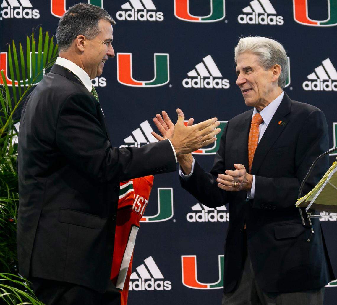 Mario Cristobal, the newly hired head football coach of the Miami Hurricanes, shakes hands with University of Miami President Julio Frenk during a press conference at the Carol Soffer Indoor Practice Facility inside the University of Miami in Coral Gables, Florida on Tuesday, December 7, 2021.