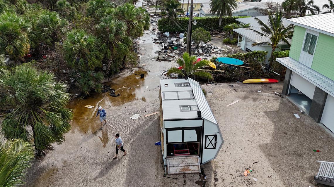 Karre Willis, right, and her husband walk through their neighborhood surveying damage and debris in front of their neighbors’ homes in Charlotte County near Manasota Key on Thursday, Oct. 10, 2024, the morning after Hurricane Milton hit the area.