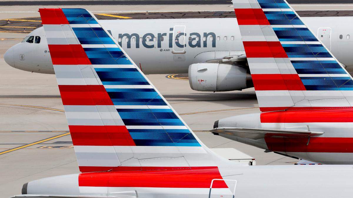 In this Wednesday, March 25, 2020, file photo, American Airlines jets sit idly at their gates as a jet arrives at Sky Harbor International Airport in Phoenix.