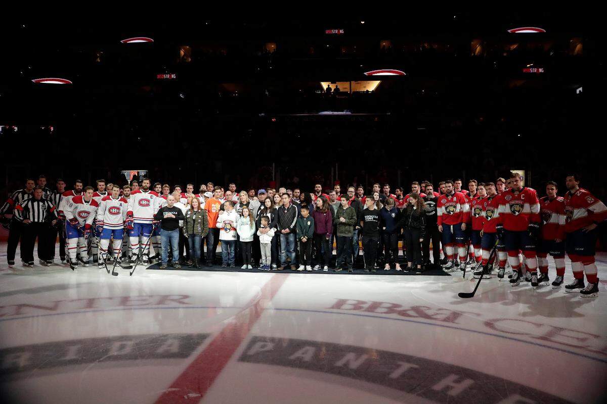 Survivors and family members pose on the ice in honor of the survivors of a mass school shooting at Marjory Stoneman Douglas High School before an NHL hockey game where the Montreal Canadiens play the Florida Panthers on Sunday, Feb. 17, 2019, in Sunrise, Fla. (AP Photo/Brynn Anderson)