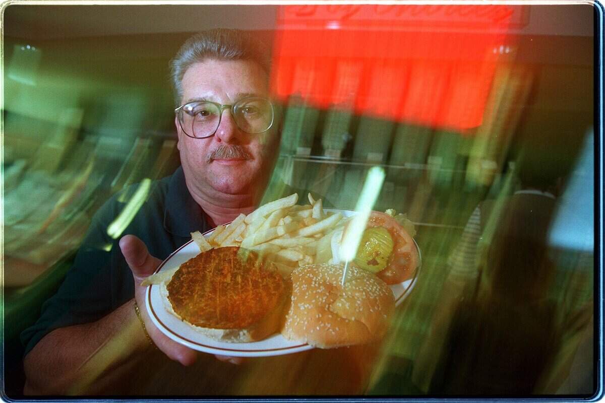 .In 1996, Rolando Pereira, general manager of La Carreta holds up a black bean burger at the MIA location.