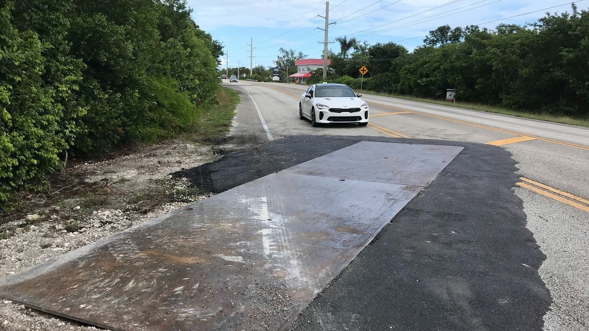 A car approaches a steel plate placed over a trench dug into U.S. 1 on Cudjoe Key in the Florida Keys.