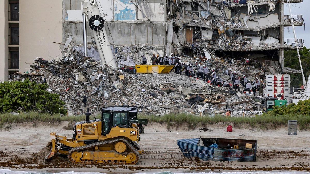 A bulldozer pulls a migrant boat that washed ashore in Surfside as search and rescue teams look for survivors at the 12-story oceanfront condo, Champlain Towers South, on Tuesday, June 29, 2021.