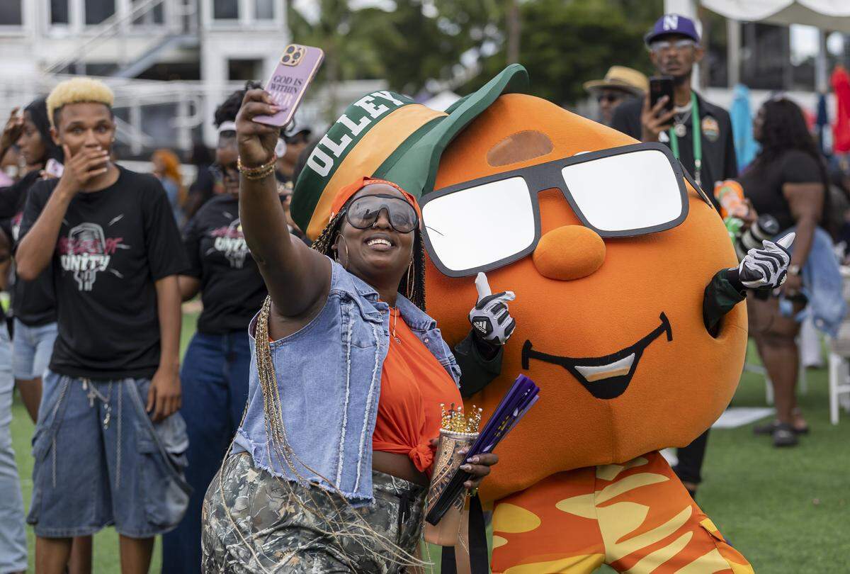 Erin Johnson takes a selfie with mascot Olley during a fan festival before the Orange Blossom Classic football game between the Florida A&M Rattlers and the Howard Bison at Hard Rock Stadium on Saturday, Aug. 30, 2025, in Miami Gardens, Fla.