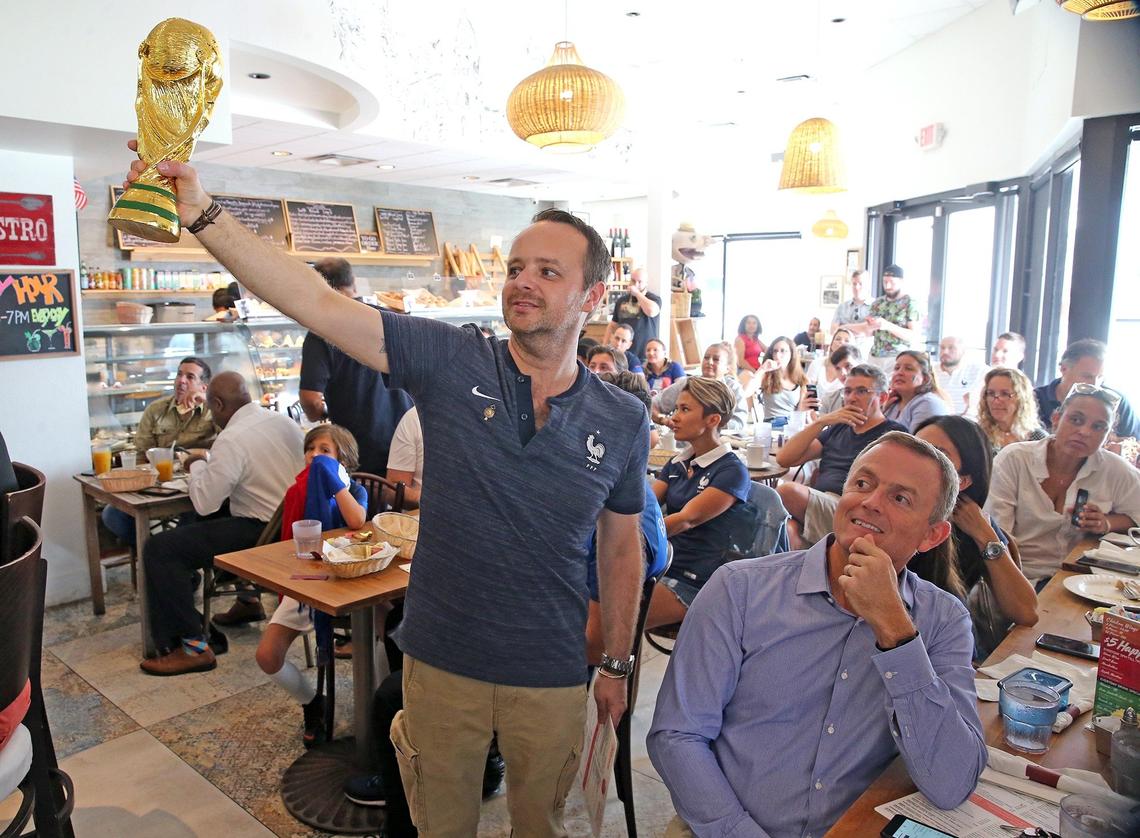 Cory Finot, owner of Cafe Creme on Northeast 125th Street in North Miami, holds a replica of the World Cup trophy as guests at his restaurant watch France play against Uruguay, July 6, 2018.