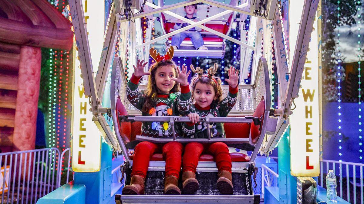 Sister, Alicia, 4, and Olivia Gomes, 3, react while on an amusement ride at Christmas Wonderland at Tropical Park, a Miami-style holiday celebration of flavor and culture in Miami, Florida on Thursday, November 13, 2025.