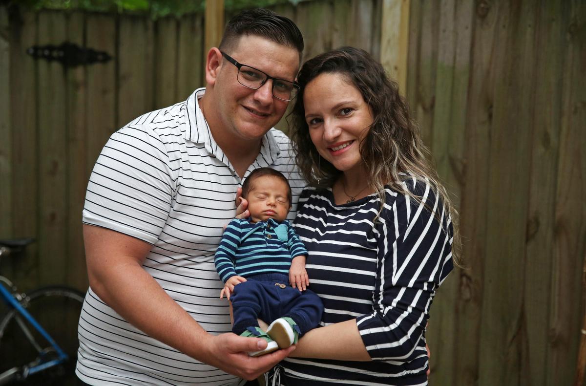 Alex Alvarez Garcia and his wife, Naiviv Perera Morales hold their newborn son, Alan, outside a cottage in Miami Springs that they are renting from a family member. The couple found themselves stuck in Miami during the pandemic and unable to travel back to their home in Uruguay to have their son as planned.